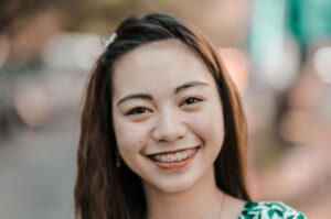 Close-up portrait of a smiling woman with braces, conveying joy and confidence outdoors.