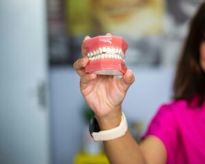 A dentist's hand holding a dental teeth model indoors. Ideal for dental care concepts.